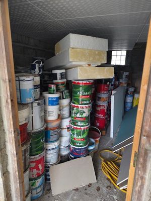 several cans of paint are stacked on top of each other in a shed