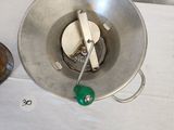 a silver bowl with a green handle on a white table