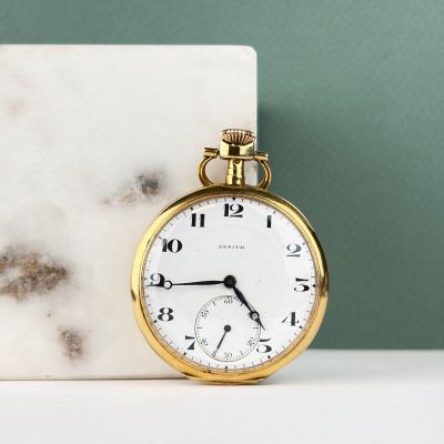 une montre de poche en or posée à côté d'un bloc de marbre