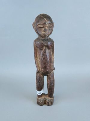 une vieille statue en bois représentant un homme debout, les mains dans les poches
