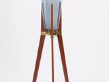 a blue glass lamp on a wooden tripod stand