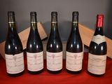 six bottles of wine are lined up on a red cloth