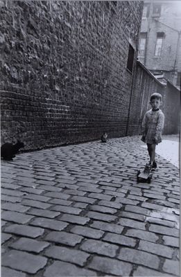 photographie en noir et blanc d'un petit garçon marchant dans une rue pavée