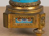a gold and blue vase on a stand on a table