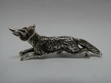 une figurine représentant un renard argenté sur fond blanc