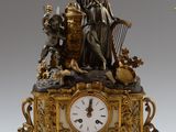 une horloge surmontée d'une statue, à côté d'un vase