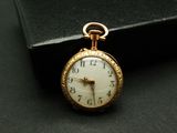 une montre de poche en or posée sur un coffret noir