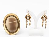 two pairs of earrings and a broochet on a white stand