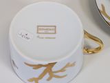 a white and gold cup and saucer sitting on a table