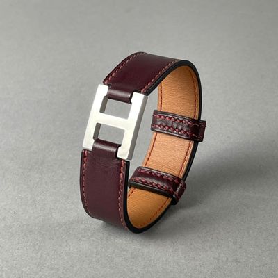 un gros plan d'un bracelet en cuir marron posé sur une surface grise