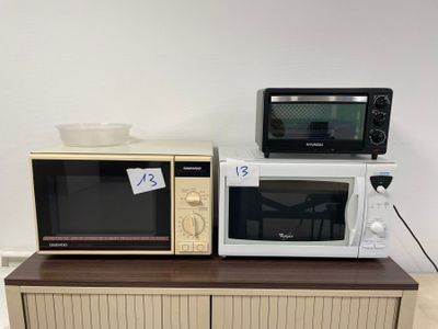 two microwaves sitting on top of a dresser in a room