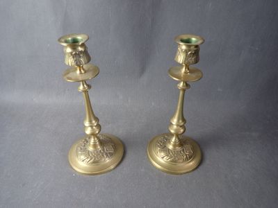 pair of antique brass candlesticks on a grey background