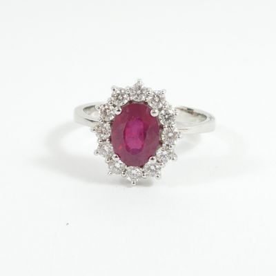a close up of a ring with a ruby stone surrounded by diamonds