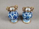 pair of blue and white vases with gold handles on a gray surface
