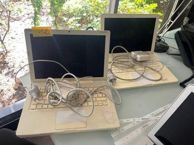 two laptops sitting on a table with wires on them