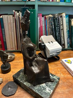 a statue of a woman sitting on a table next to a book