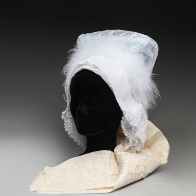 une image représentant un chapeau blanc orné de plumes, posé sur la tête d'un mannequin
