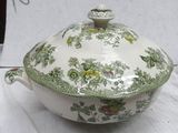 a green and white bowl with a lid on a table