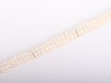 a close up of a white pearl bracelet on a white background