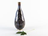a black vase with a leaf on the ground
