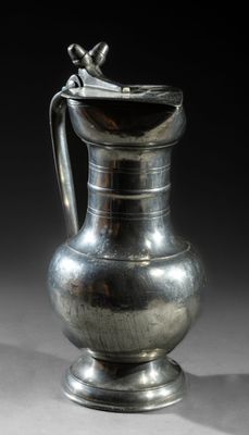 an antique silver pitcher with a bird on the handle