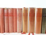 several old books are lined up on a shelf in front of a white background