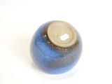 a blue vase with a brown lid sitting on a white surface