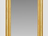 un miroir à cadre doré accroché au mur, à côté d'un mur blanc