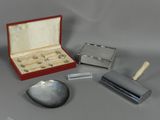 une boîte contenant des objets en argent posée sur une table, à côté d'un couteau et d'autres objets