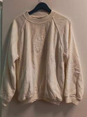 Le pull est suspendu à un cintre dans un coin de la pièce.