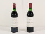 two bottles of red wine sitting next to each other on a table