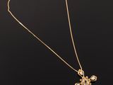 a gold necklace with a cross pendant on a black background