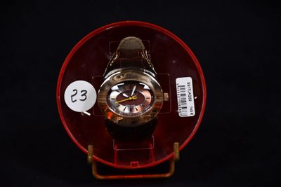une montre posée sur une assiette rouge, avec une étiquette de prix dessus
