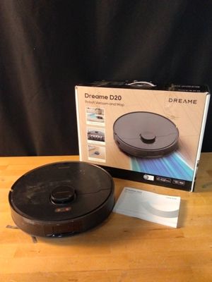 la boîte est ouverte sur la table, à côté de l'aspirateur robot