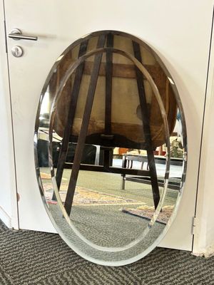 a round mirror on the floor next to a chair