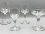 quatre verres à vin vides sont alignés sur une surface blanche
