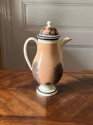 une cafetière posée sur une table en bois, avec son couvercle