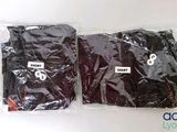 two bags of black clothing sitting on a white surface