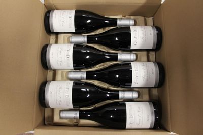 six bottles of wine in a cardboard box on a table