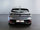 the rear end of a silver car in a room with a white wall