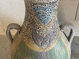 a vase that is sitting on the floor next to a wall