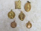 quatre pendentifs religieux en or et en argent posés sur une surface en marbre
