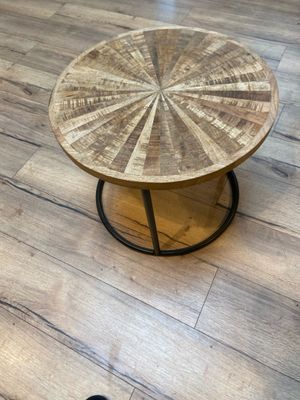 une table en bois avec un plateau rond posée sur un parquet