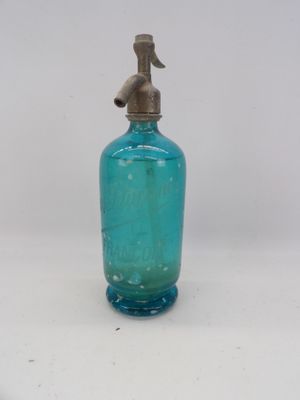a blue glass bottle with a metal spout on a white surface
