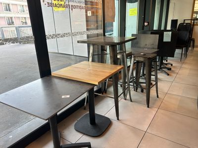 tables and stools in front of a large window in a restaurant