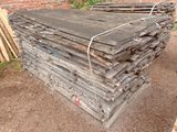 un tas de bois posé par terre à côté d'un mur de briques