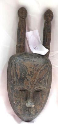 une image représentant un masque en bois sur fond blanc, avec un morceau de papier