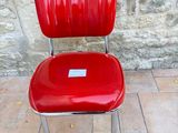a red chair that is sitting in front of a stone wall
