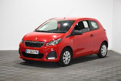 une voiture rouge est garée dans une pièce au sol en damier