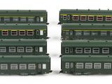 two green trains sitting side by side on a white surface